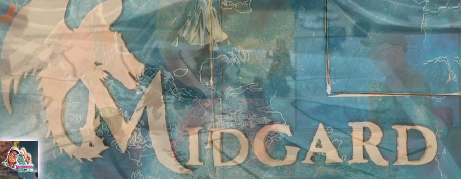 Ausschnitt einer "MIDGARD - Legenden von Damatu" - Torte. Darauf ist das Logo von "MIDGARD - Legenden von Damatu" zu sehen. Unten links befindet sich wiederum das quadratische Logo von "SteamTinkerers Klönschnack".
